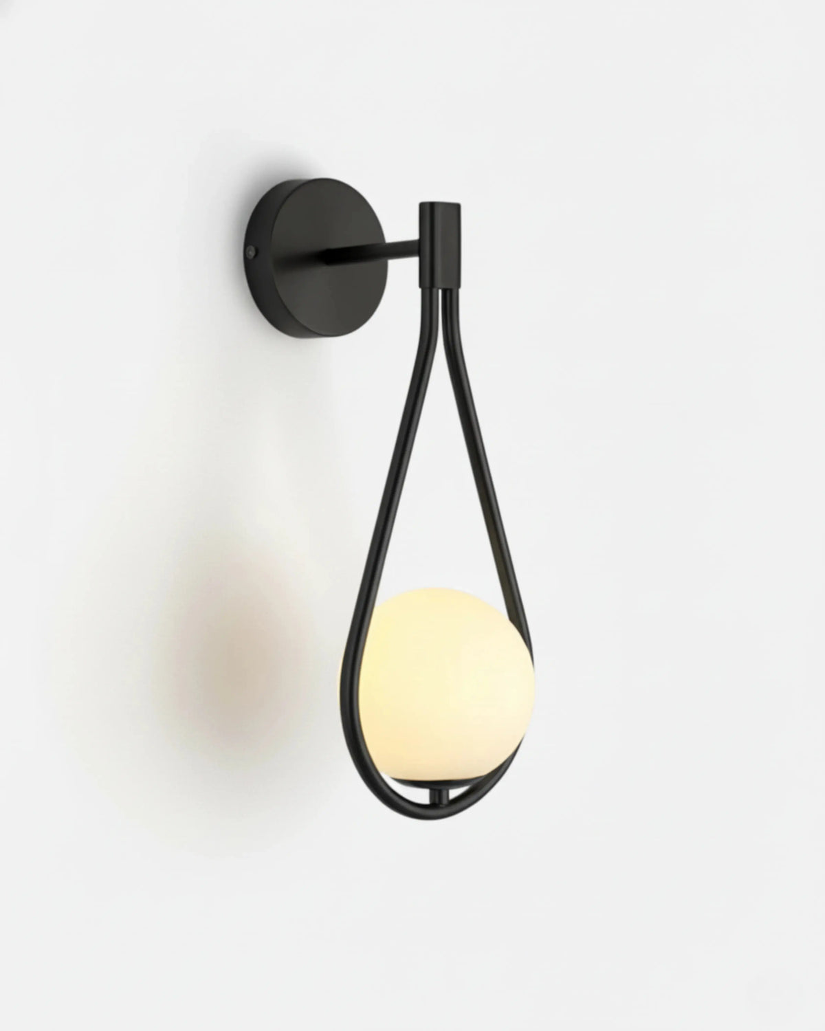 Globe wall sconce FILO No.01 in Matte Black, lit opal globe hanging in a slim black looped bracket