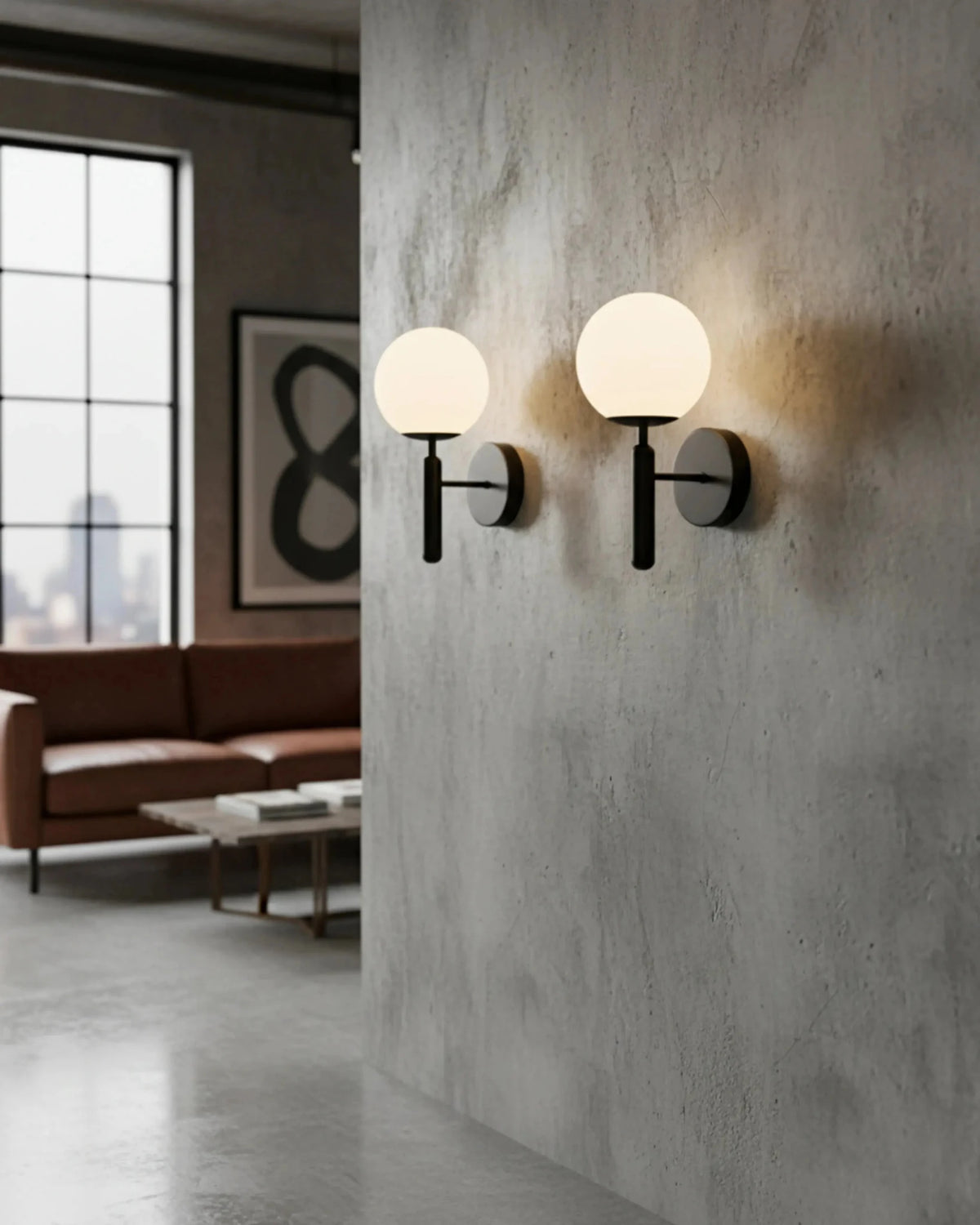 Pair of globe wall sconces CIELO No.01 in matte black lit on a concrete wall in a loft living room
