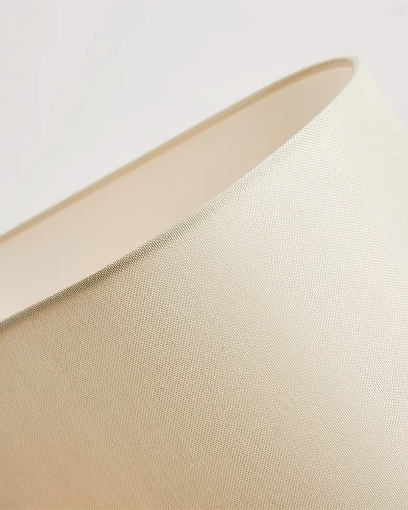 Close-up of the cream linen drum shade of the linen shade table lamp ROCCA No.02 against a white background
