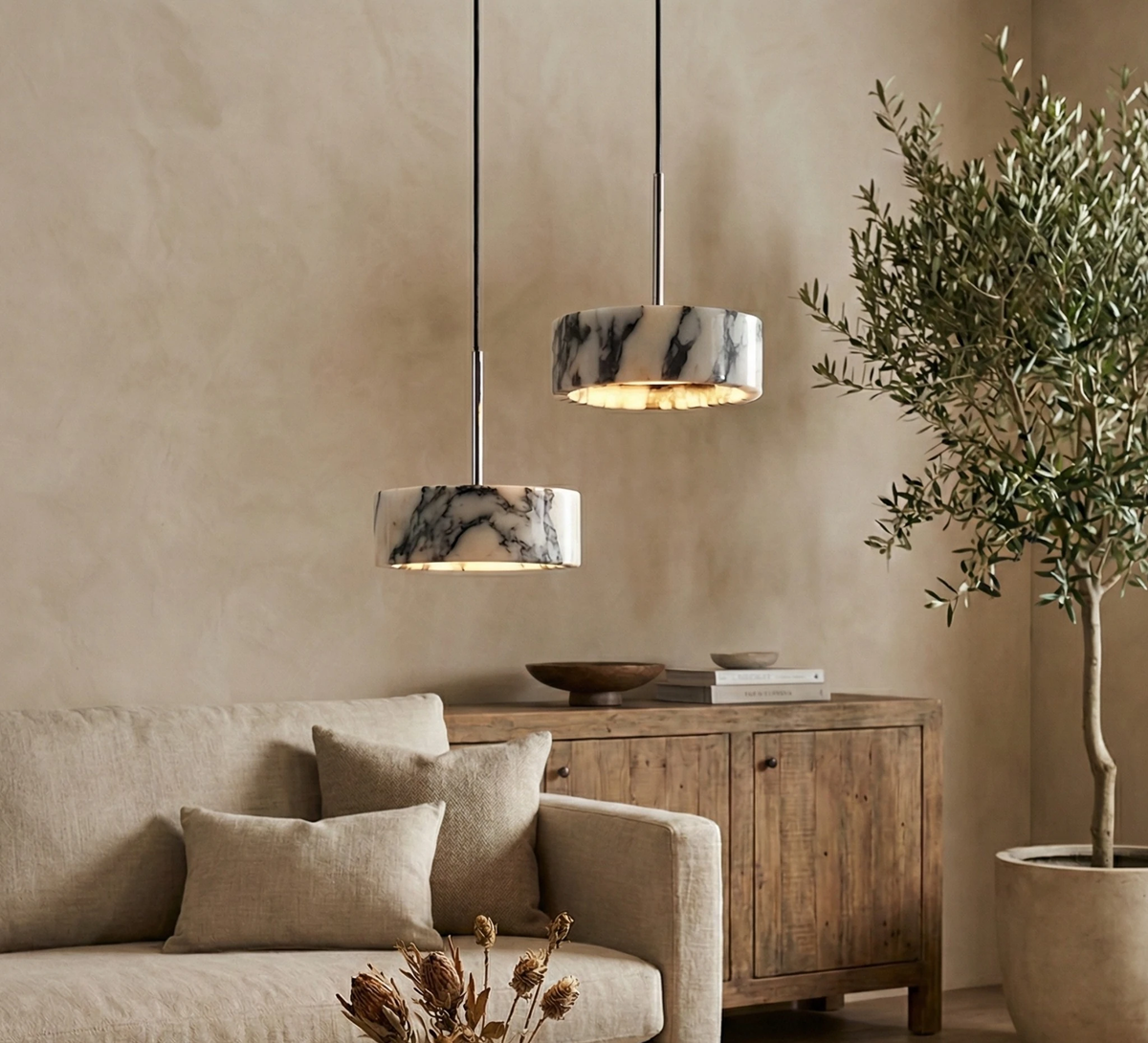 Marble pendant light MARMI No.01 halo lit above a wooden sideboard with a sofa and olive tree in a living room