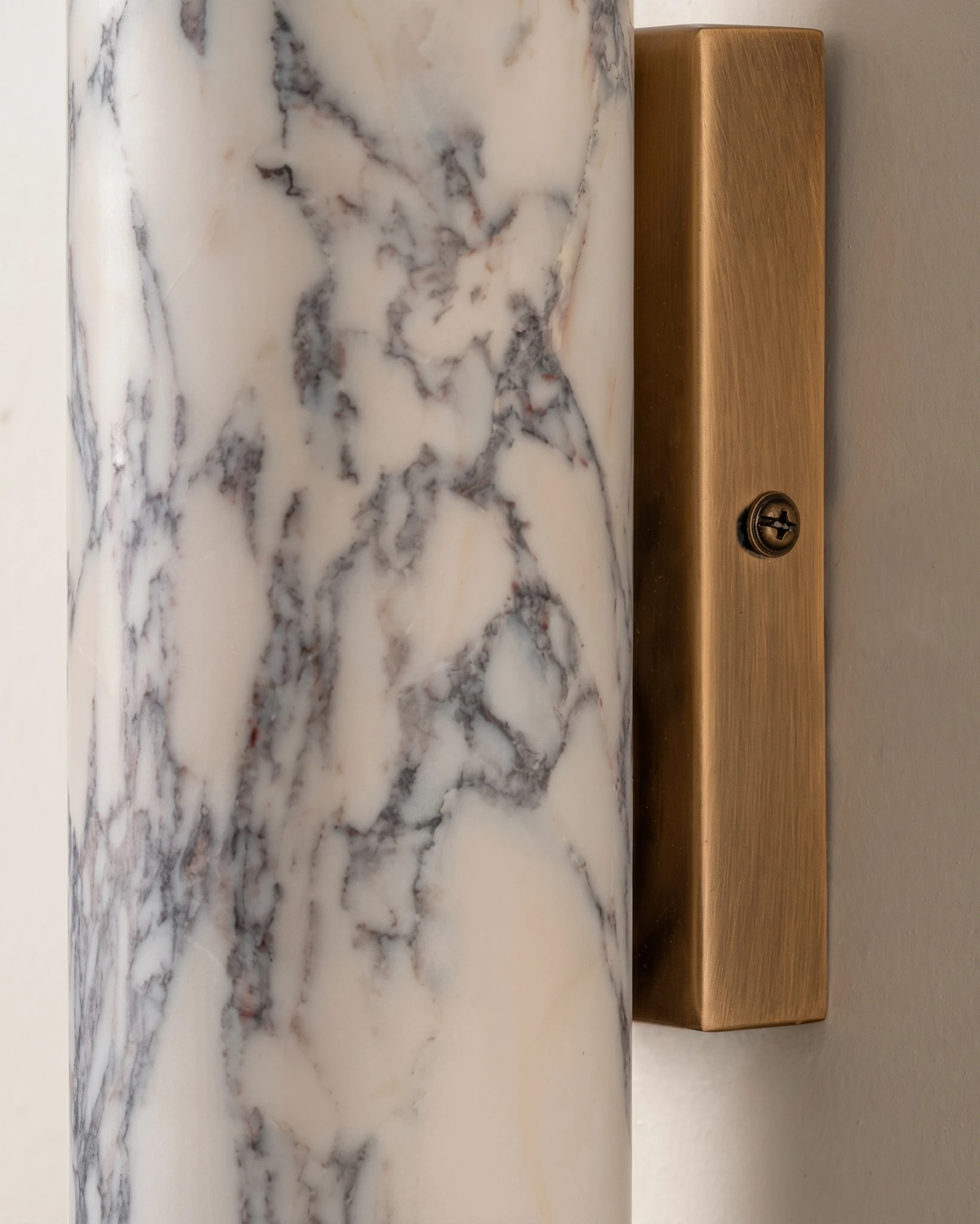 Close-up of the brass bracket and veined marble cylinder of the marble wall sconce PORTORO No.01