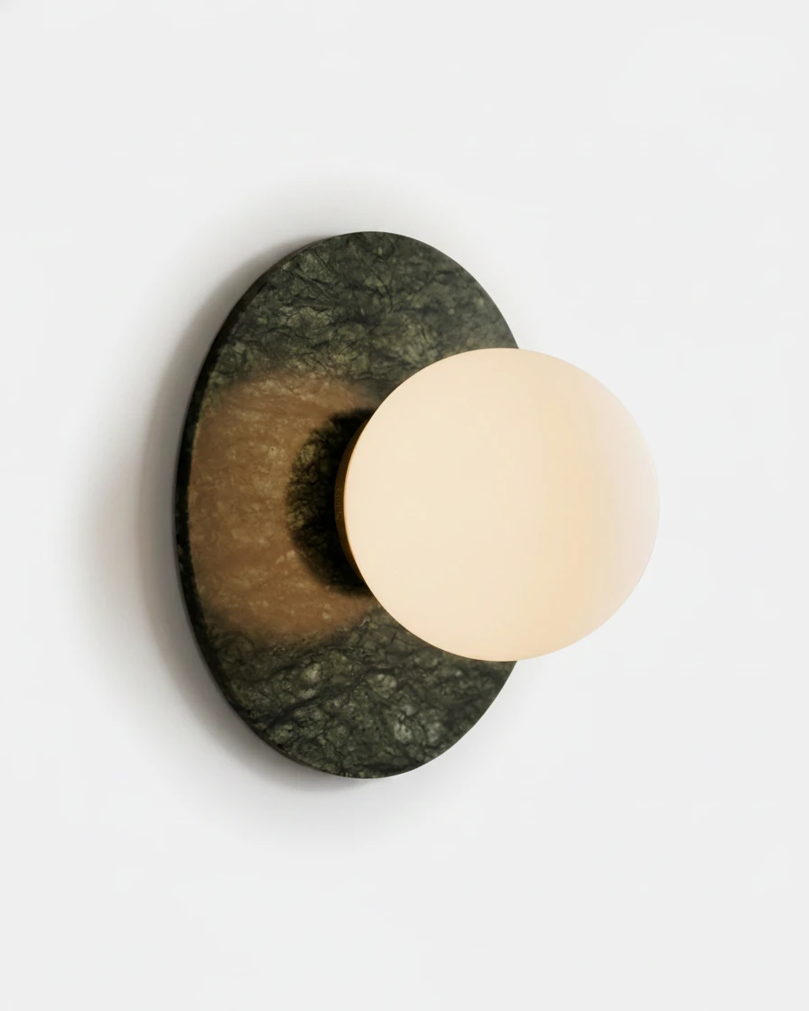 Marble wall sconce VENA No.01, emerald green marble disc with a glowing opal glass globe on a white wall