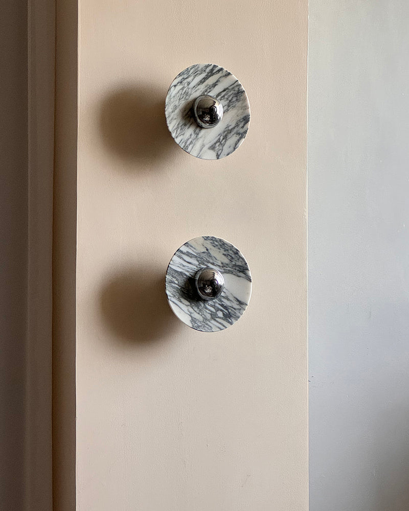 Marble wall sconce LATTE No.01 pair in gray-veined marble with chrome centers stacked on a cream wall, unlit