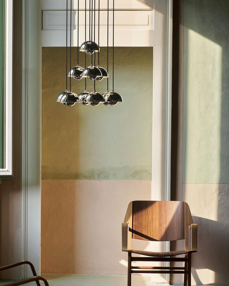 Modern chandelier FLORA No.01 in chrome mirror finish hanging in a green plaster room, closer view by a wood armchair