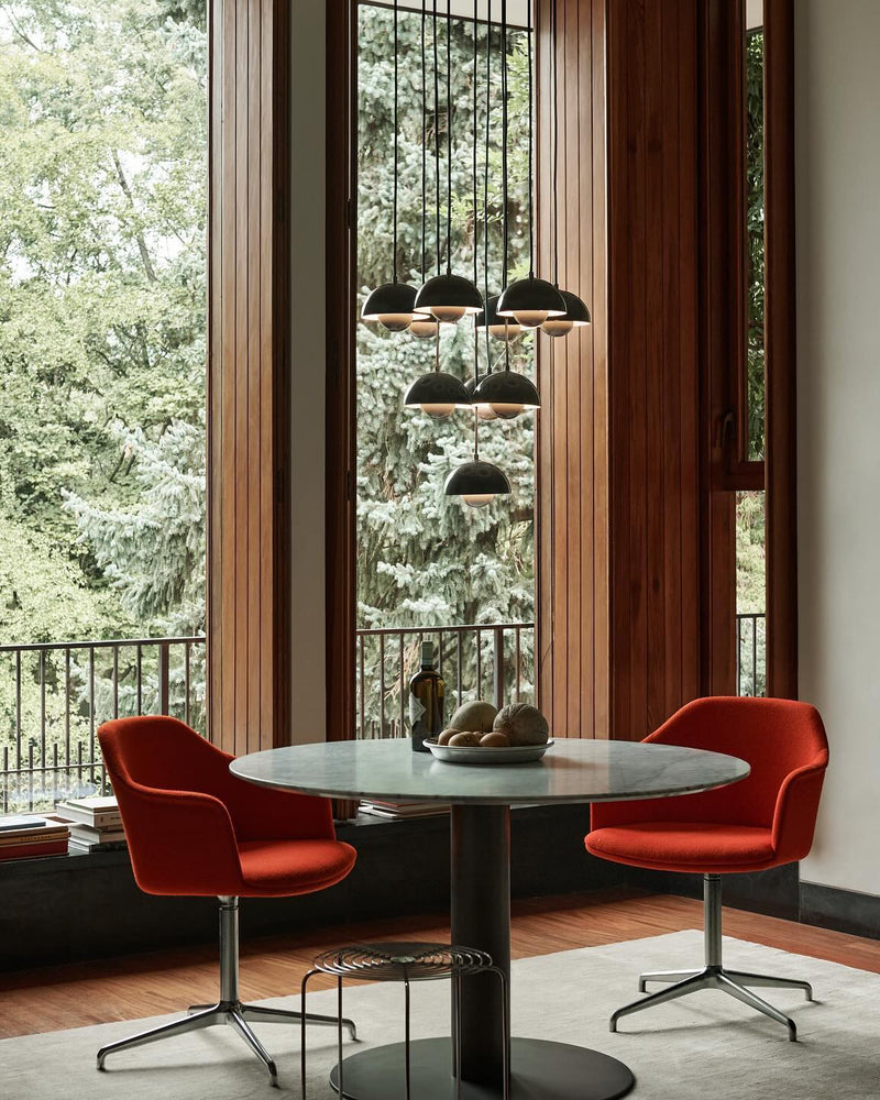 Modern chandelier FLORA No.01 with dark petal globes above a round table and two red chairs at tall windows