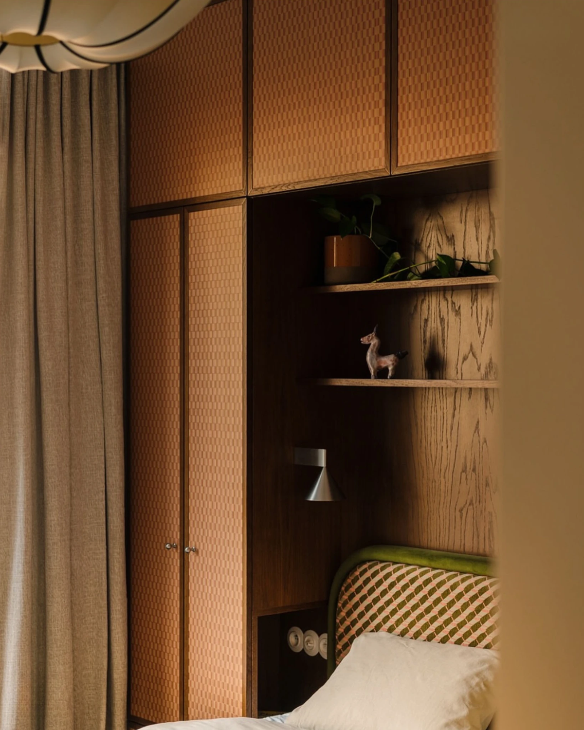 Modern wall sconce ETNA No.01 in aluminum switched on inside a cane-paneled bedroom alcove beside the bed