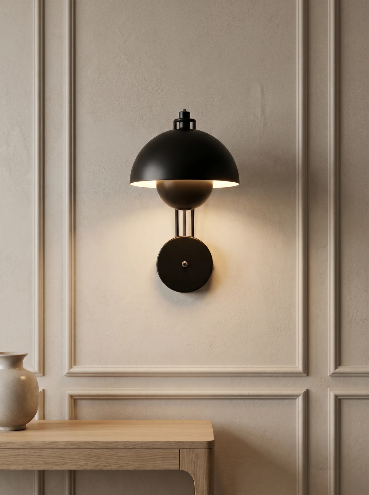 Modern wall sconce CRETA No.01 in black, nested mushroom dome switched on above a pale oak console on a paneled wall