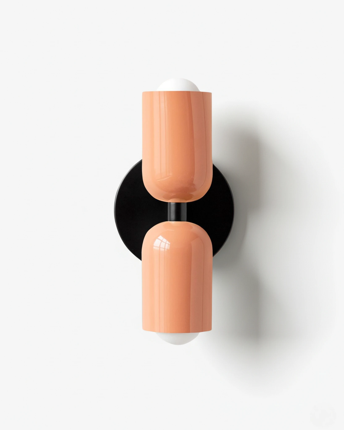 Modern wall sconce TORINO No.01 in Pink & Pink, salmon pink capsules top and bottom on a black round backplate