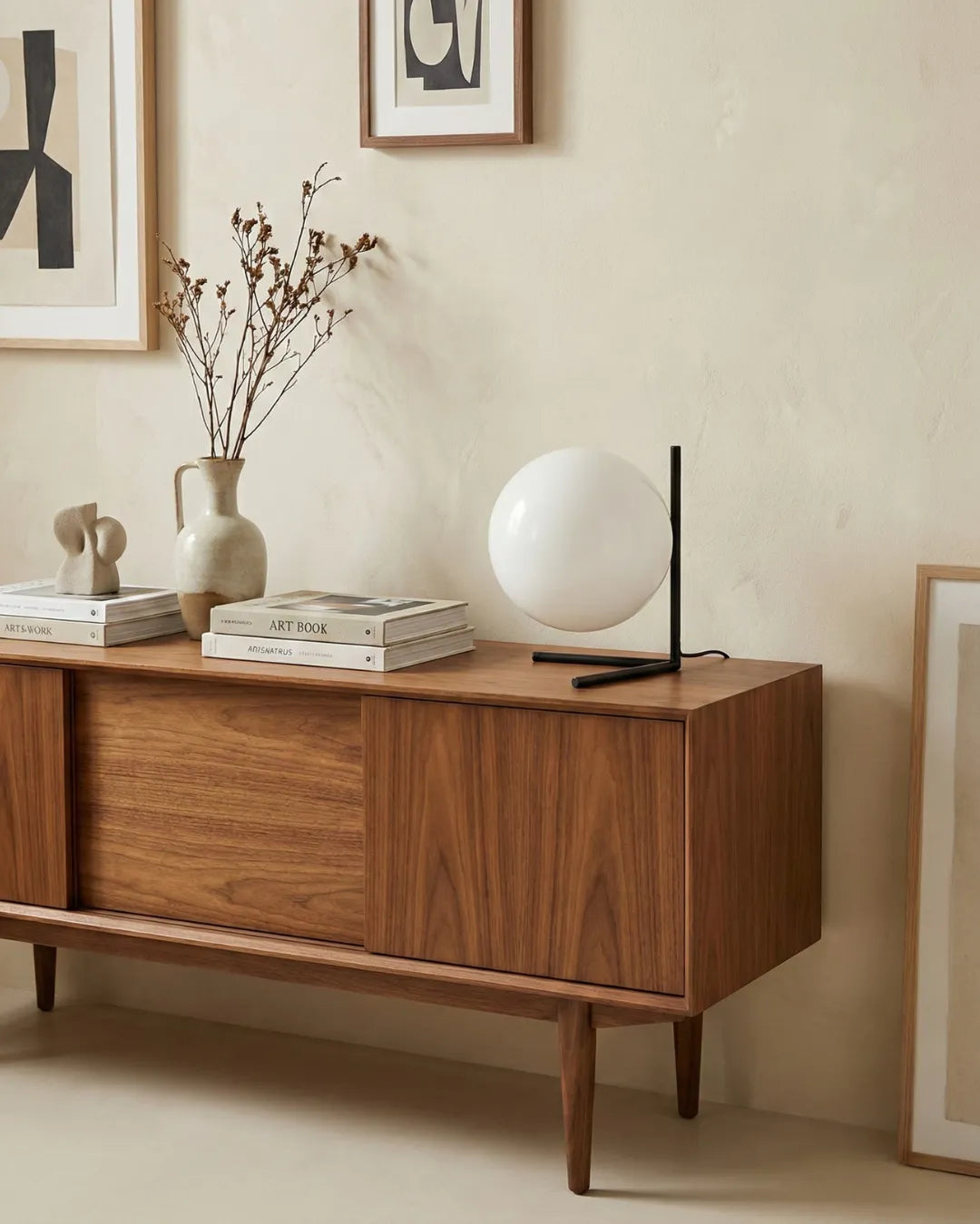 Opal globe table lamp ARIA No.01 lit on a mid-century walnut sideboard with a vase and stacked books