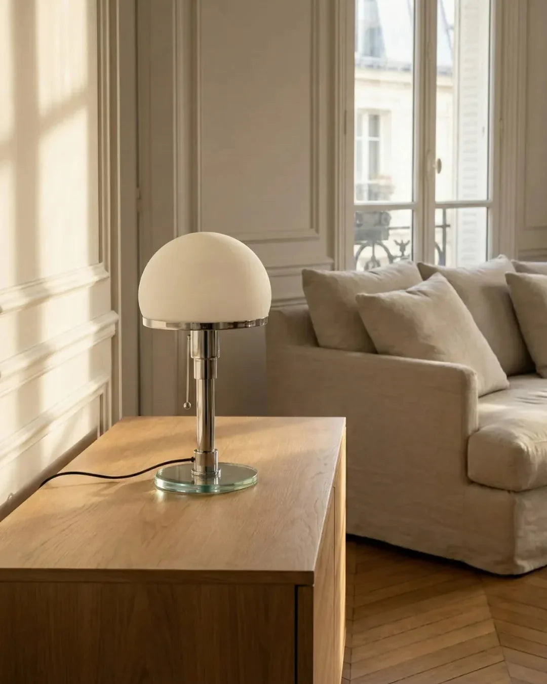 Opal globe table lamp LUMA No.01 on an oak sideboard in a paneled room with a beige sofa and tall windows