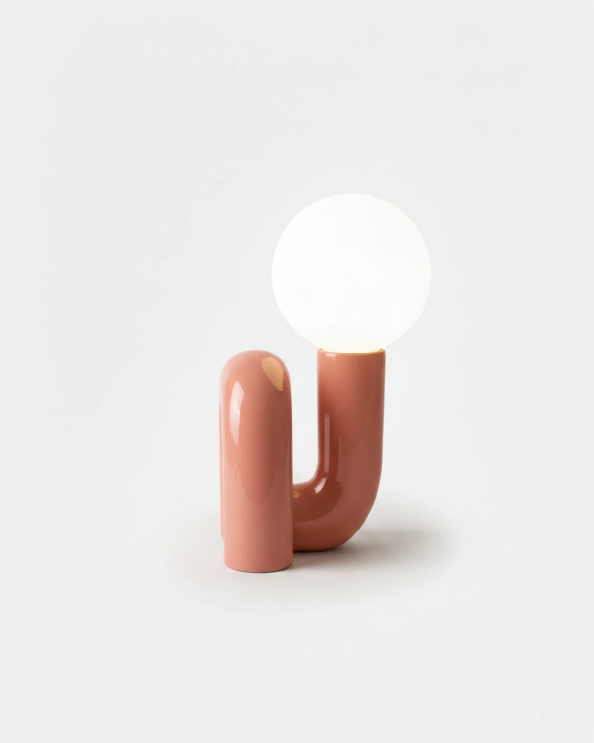 Opal globe table lamp VICO No.01 in Soft Rose, curved resin tube holding a lit frosted globe