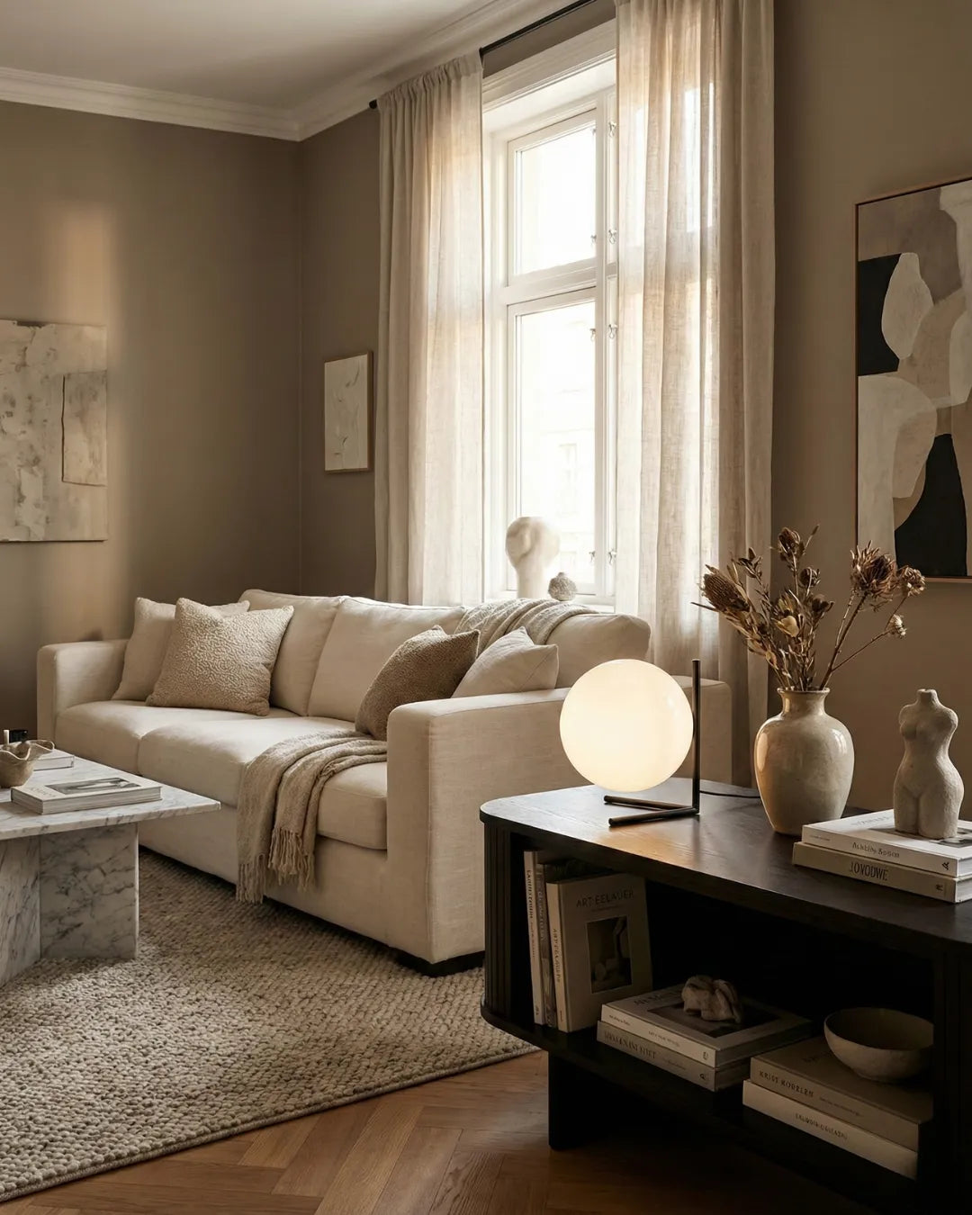 Opal globe table lamp ARIA No.01 lit on a black console beside a vase, cream sofa and tall window behind