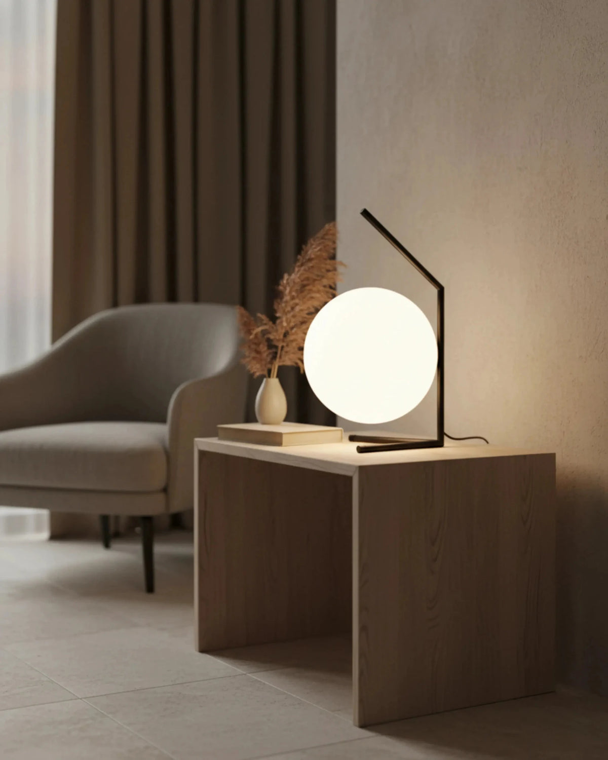 Opal globe table lamp ENNA No.01 lit on a wooden cube side table next to a gray armchair and curtain