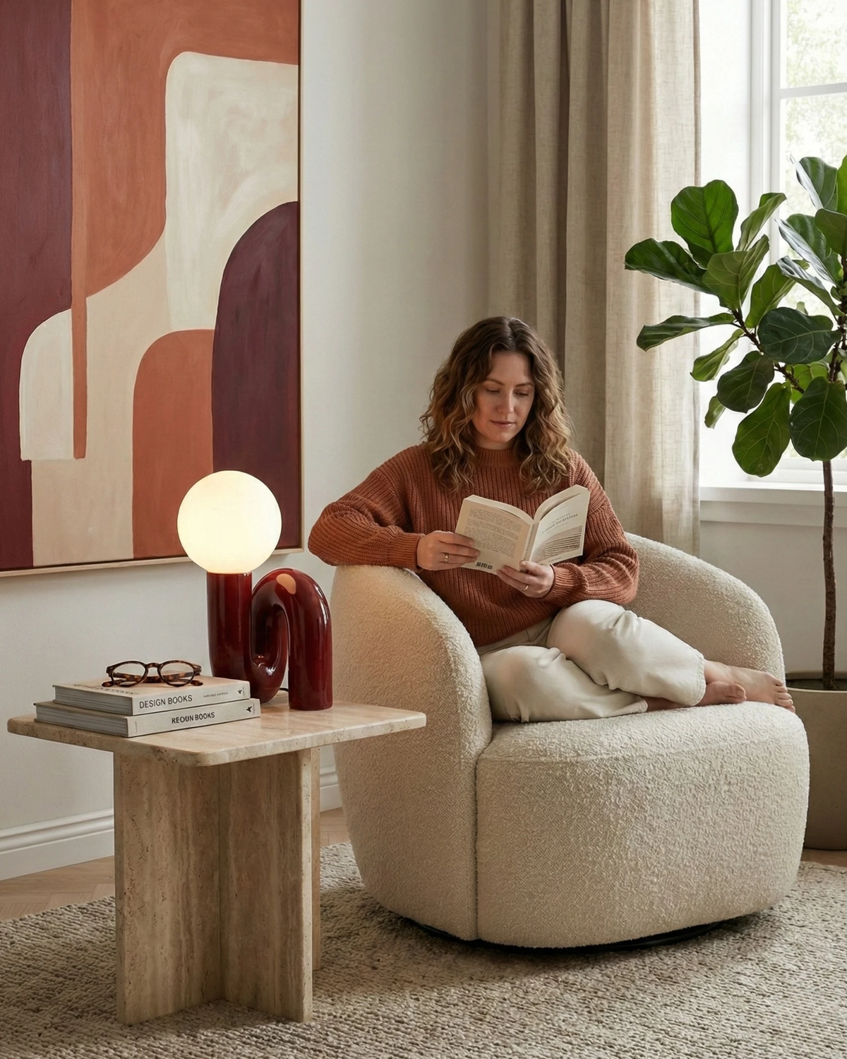 Opal globe table lamp VICO No.01 in bordeaux red lit on a travertine side table next to a woman reading in an armchair