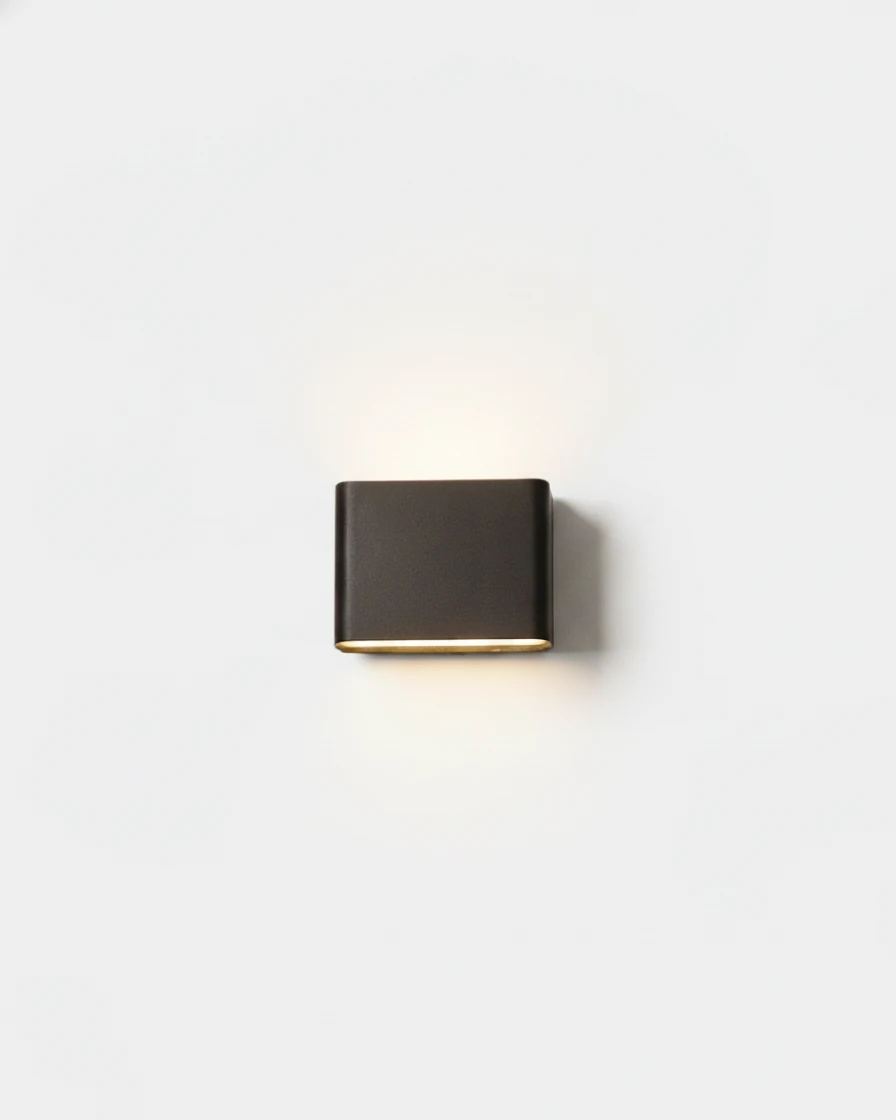 Outdoor wall sconce PISA No.01 small size in deep black, pill shape casting light up and down a white wall