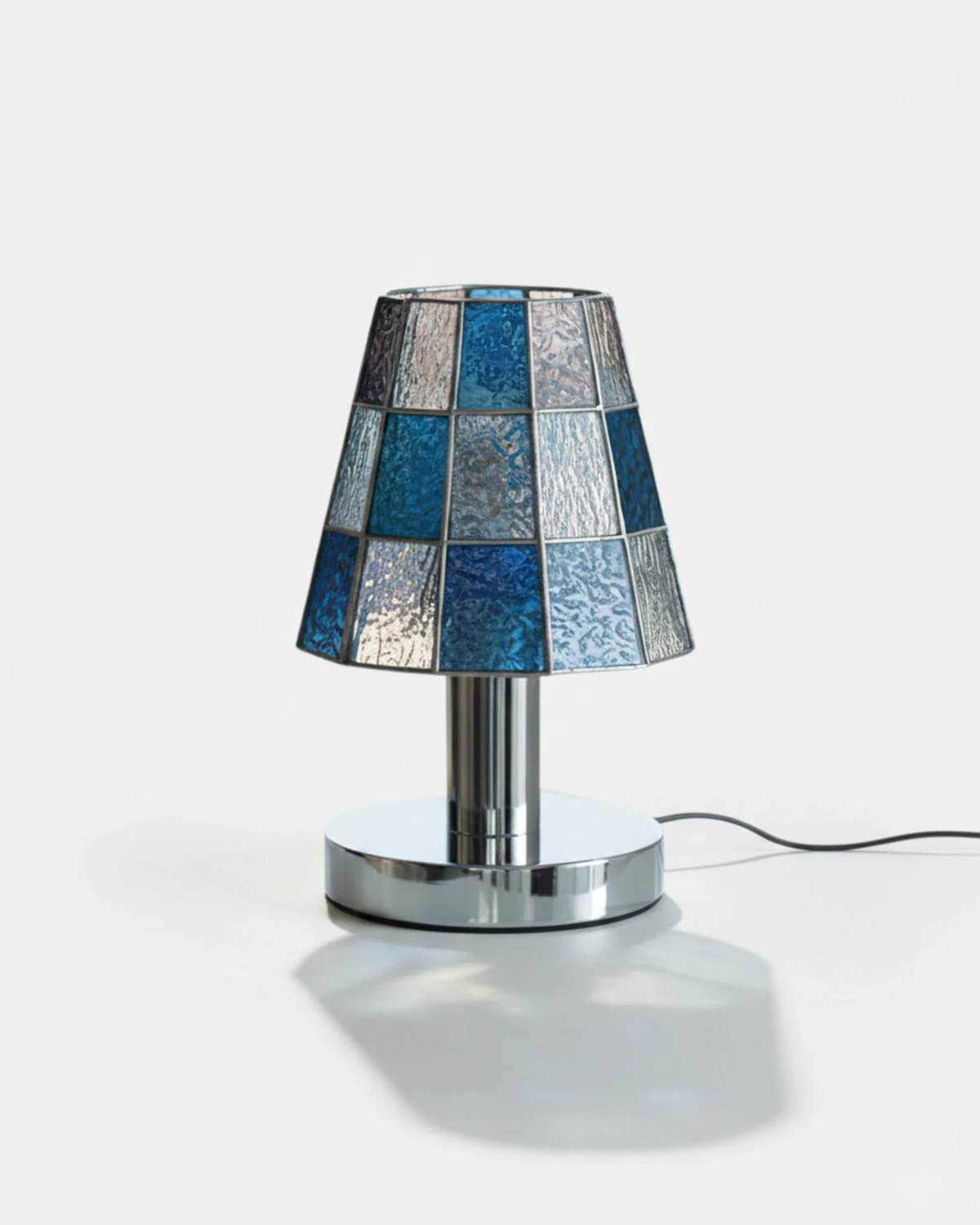 Stained glass table lamp VETRA No.01 in cobalt blue, mosaic shade on a chrome base with cord, switched on
