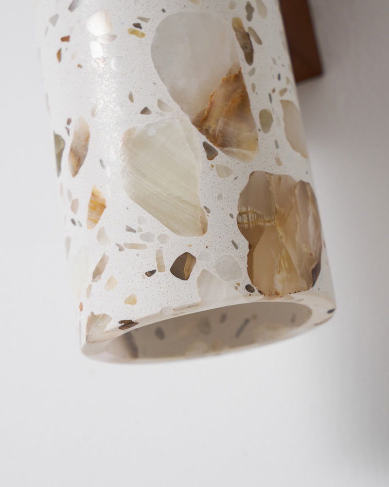 Close-up of the beige terrazzo surface of the terrazzo wall sconce INCA No.02, unlit, with its walnut block