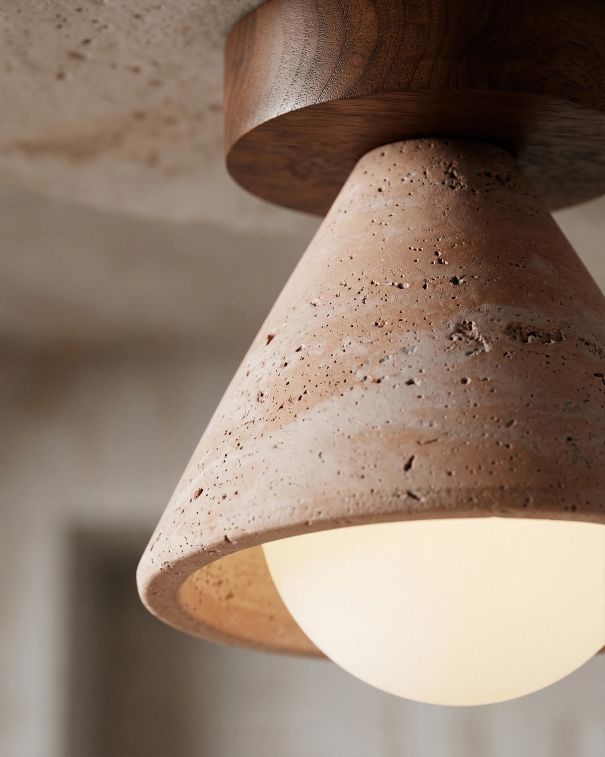 Close-up of the walnut canopy disc and travertine cone of the travertine flush mount ceiling light CIPRO No.01, lit