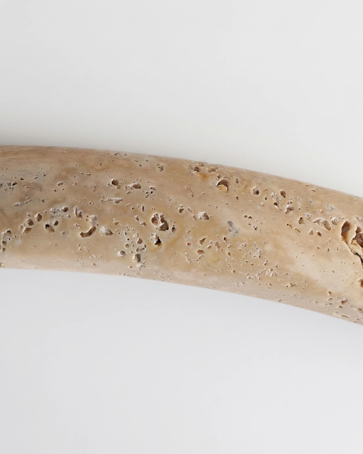 Close-up of the cream travertine rim of the LUNA No.05 travertine flush mount ceiling light with the panel lit