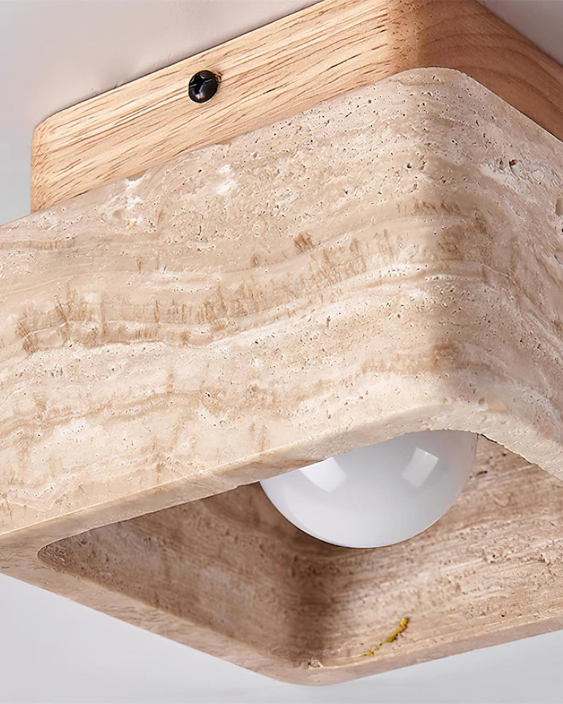 Close-up from below of the travertine flush mount ceiling light CARSO No.01 showing the bulb inside the stone block