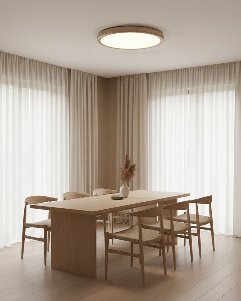 Travertine flush mount ceiling light LUNA No.05 lit above a light wood dining table with sheer curtains