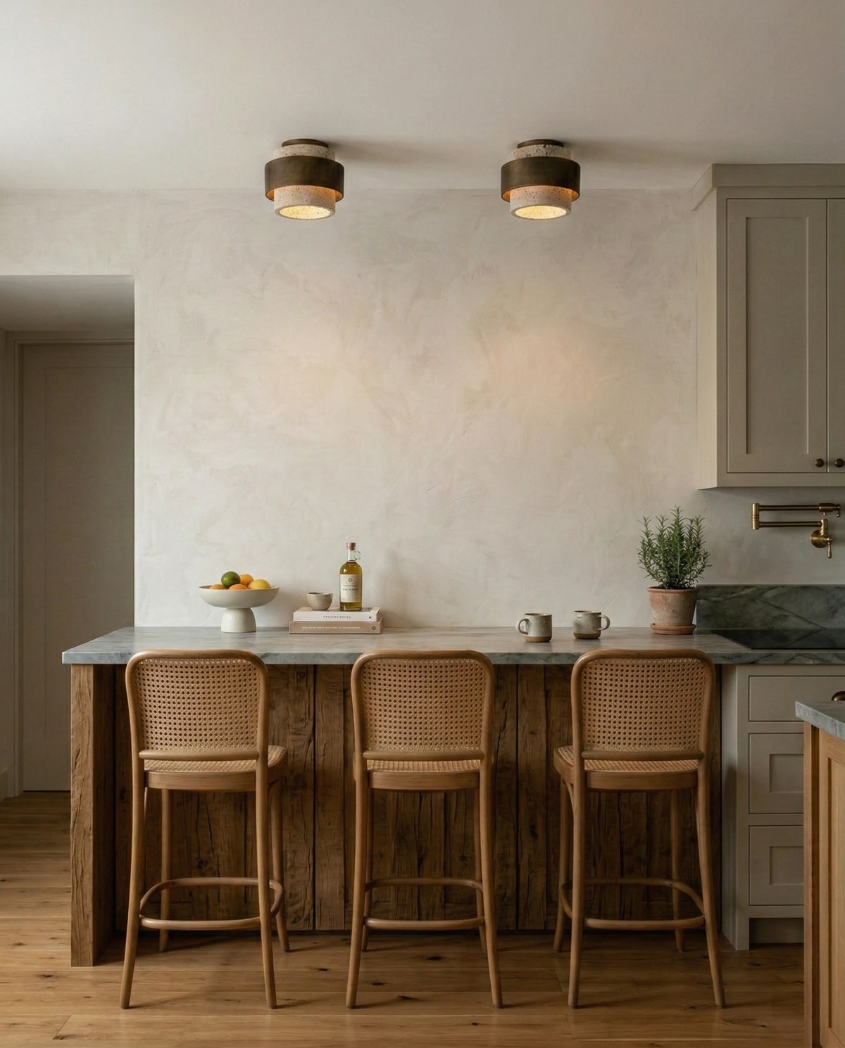 Travertine flush mount ceiling light DOMUS No.01, two units lit above a kitchen island with three rattan stools