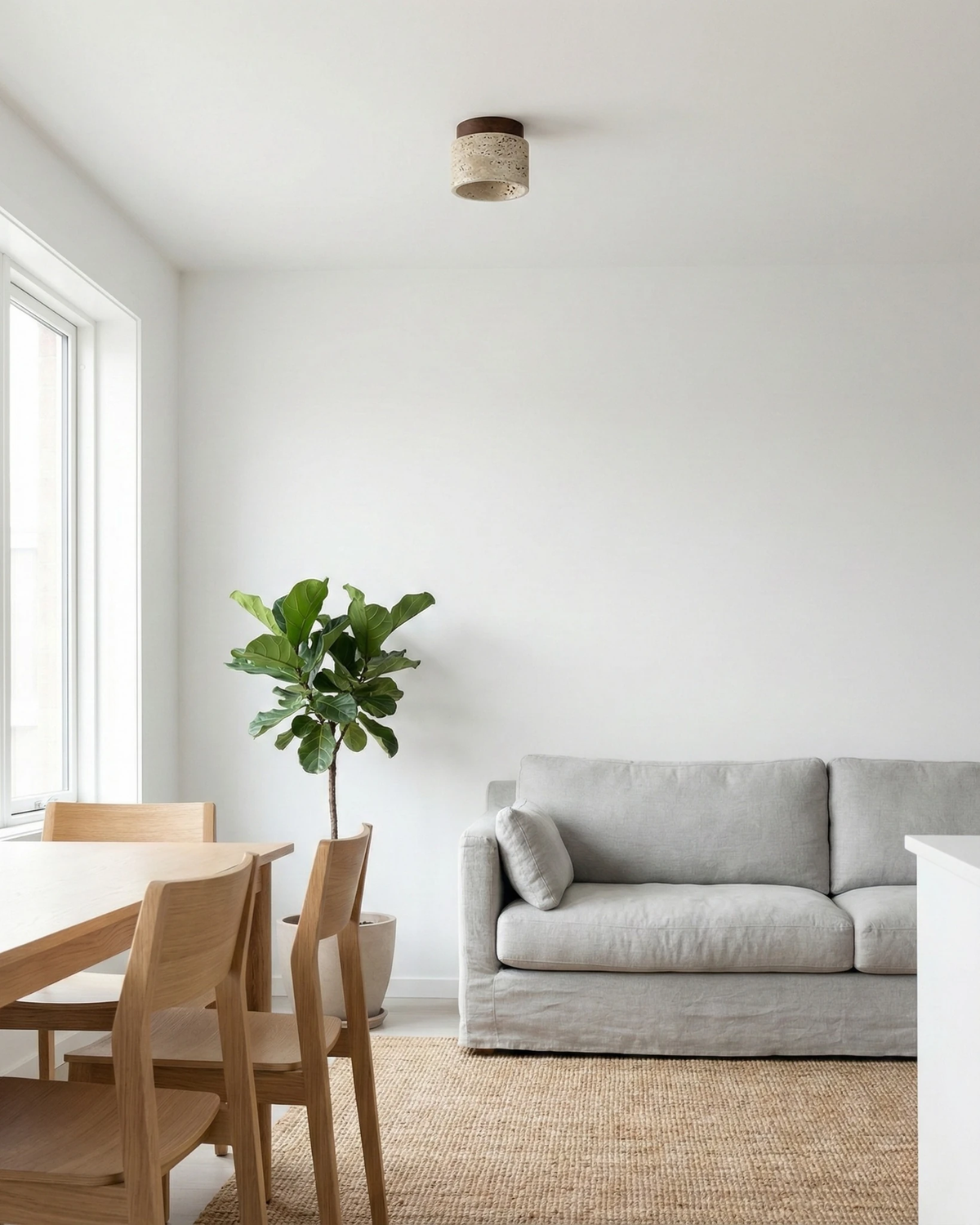 Travertine flush mount ceiling light VERTIN No.05 in cream, lit above a gray sofa and oak dining chairs in a bright room