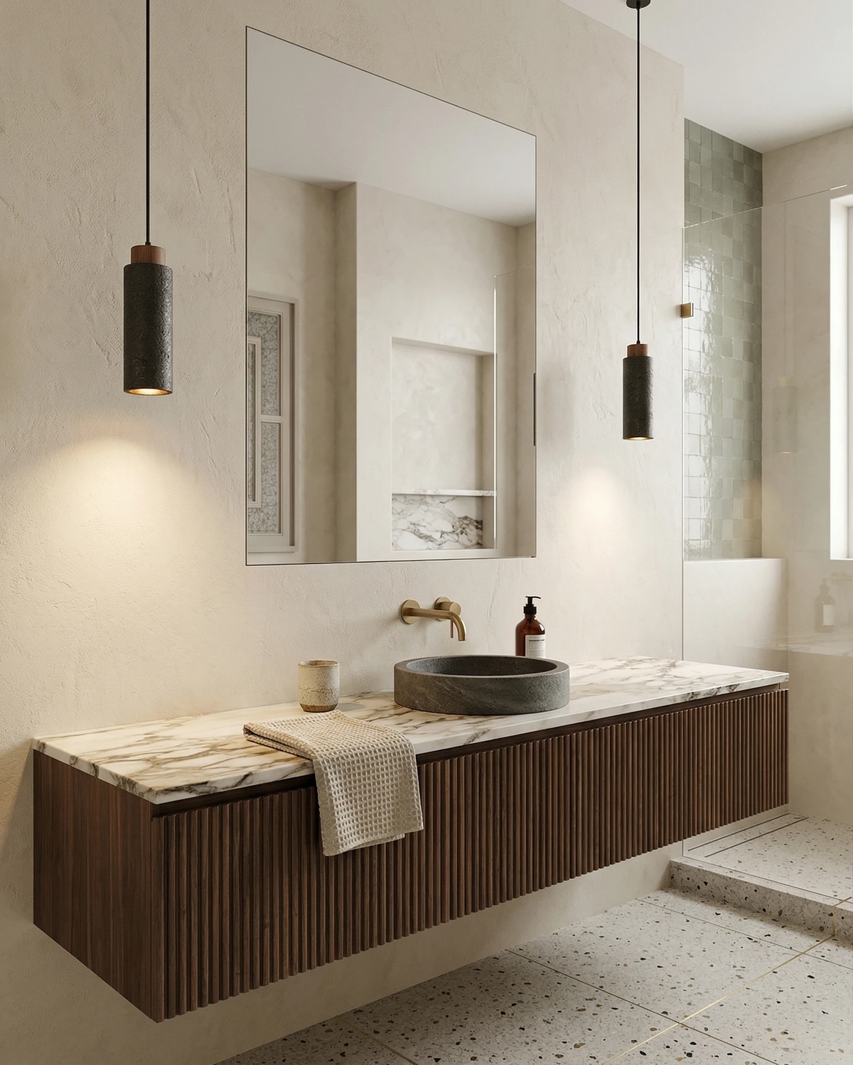 Two travertine pendant lights CORTO No.03 in Volcano Black lit beside a mirror over a floating walnut bathroom vanity