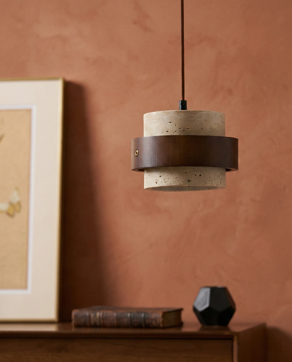 Travertine pendant light AVORIO No.05 in yellow travertine above a wooden console with framed art on a terracotta wall