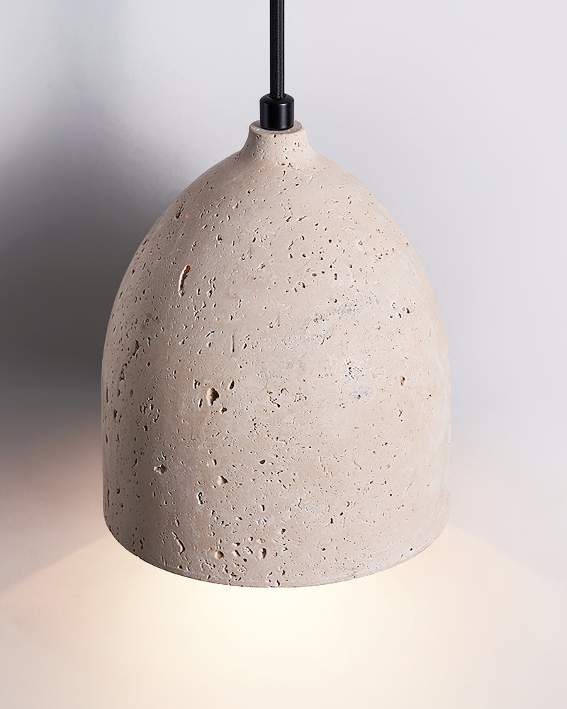 Close-up of the lit volcanic travertine bell of the BOCCA No.01 travertine pendant light with its pitted surface