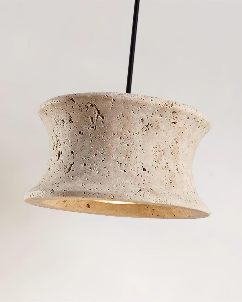 Close-up of the pitted cream travertine flared shade of the CONA No.04 travertine pendant light, glowing from below