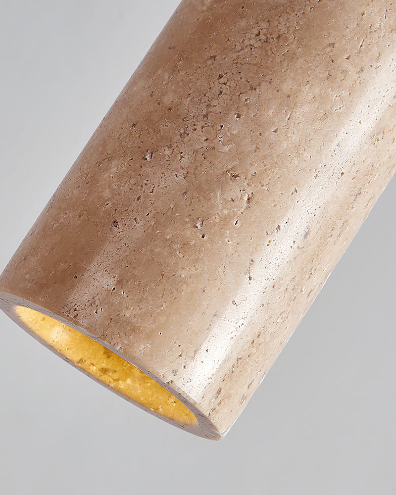 Close-up of the cream travertine pendant light CORTO No.03, porous stone cylinder lit from within at the bottom rim