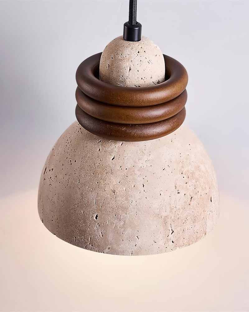 Close-up of the DOMUS No.03 travertine pendant light, pitted travertine dome and three walnut rings, lit