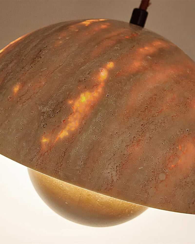 Close-up of the SOLE No.01 travertine pendant light, dome glowing amber through the stone when switched on
