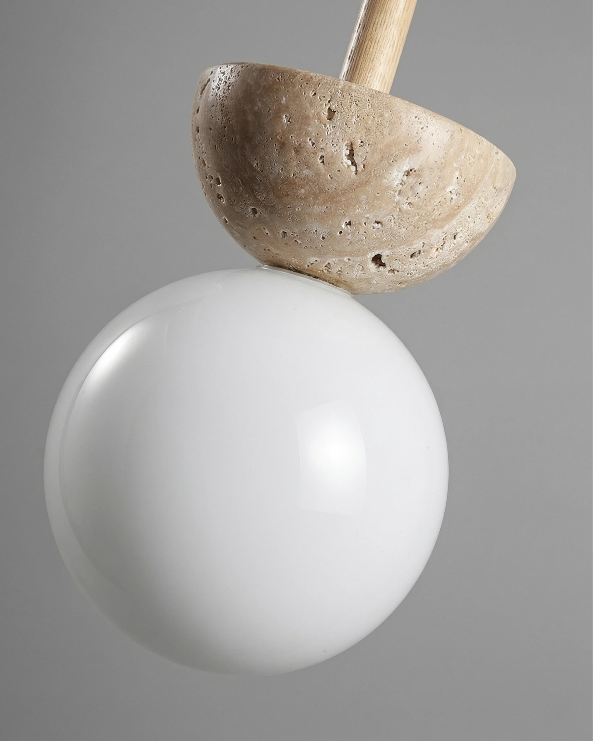 Close-up of the travertine dome resting on the opal glass globe of the SOVA No.04 travertine pendant light, unlit