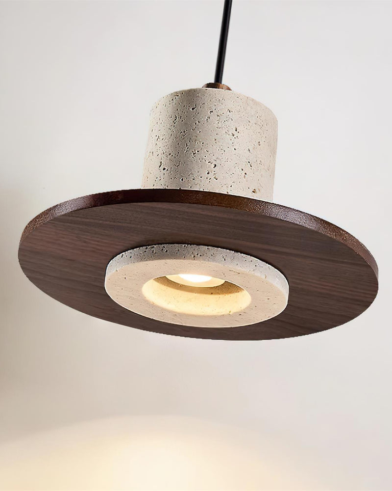 Close-up from below of the TONDO No.04 travertine pendant light showing the lit lens ringed by stone on the walnut disc