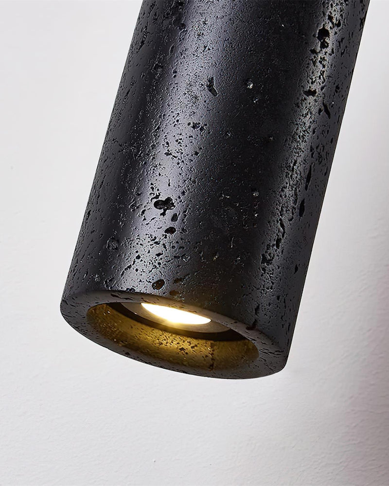 Close-up of the Volcano Black cylinder of the travertine pendant light CORTO No.03 with the LED glowing at its opening