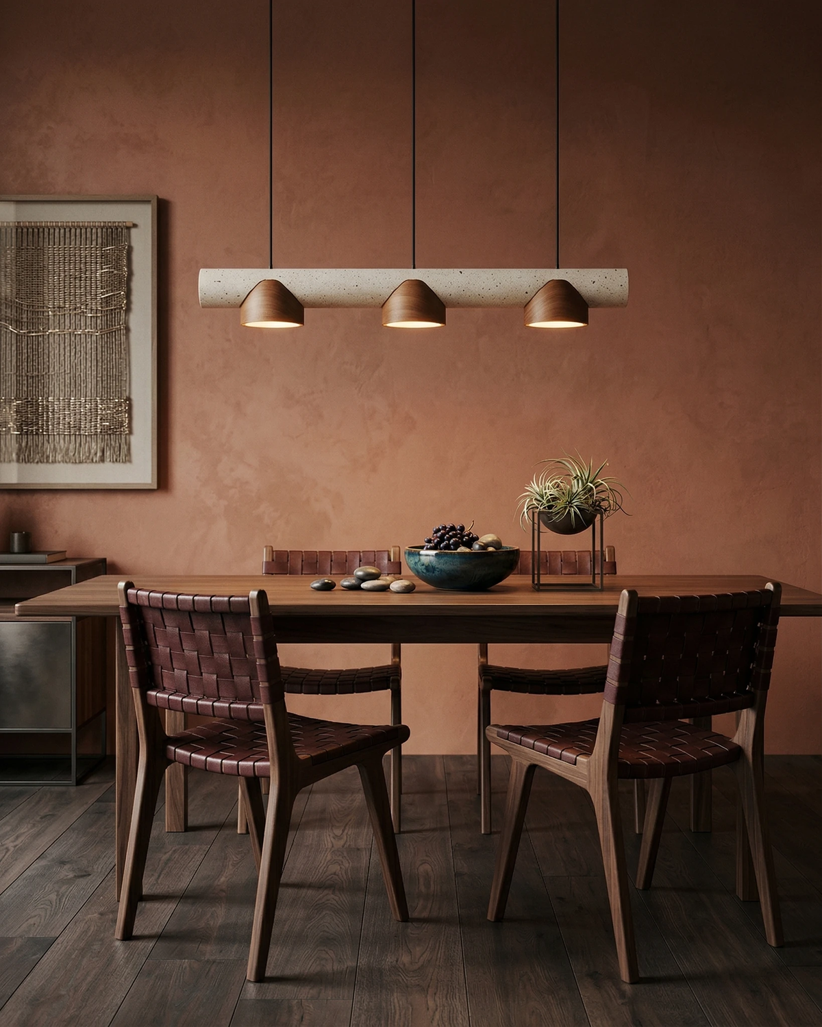 Travertine pendant light PIETRA No.06, linear bar with three walnut cones lit above a dining table by a terracotta wall