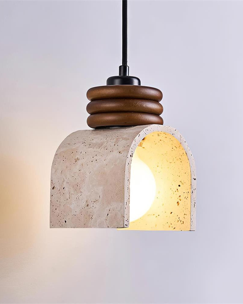 Travertine pendant light ARCA No.02 seen from the front, lit bulb inside the open arch of the travertine shade