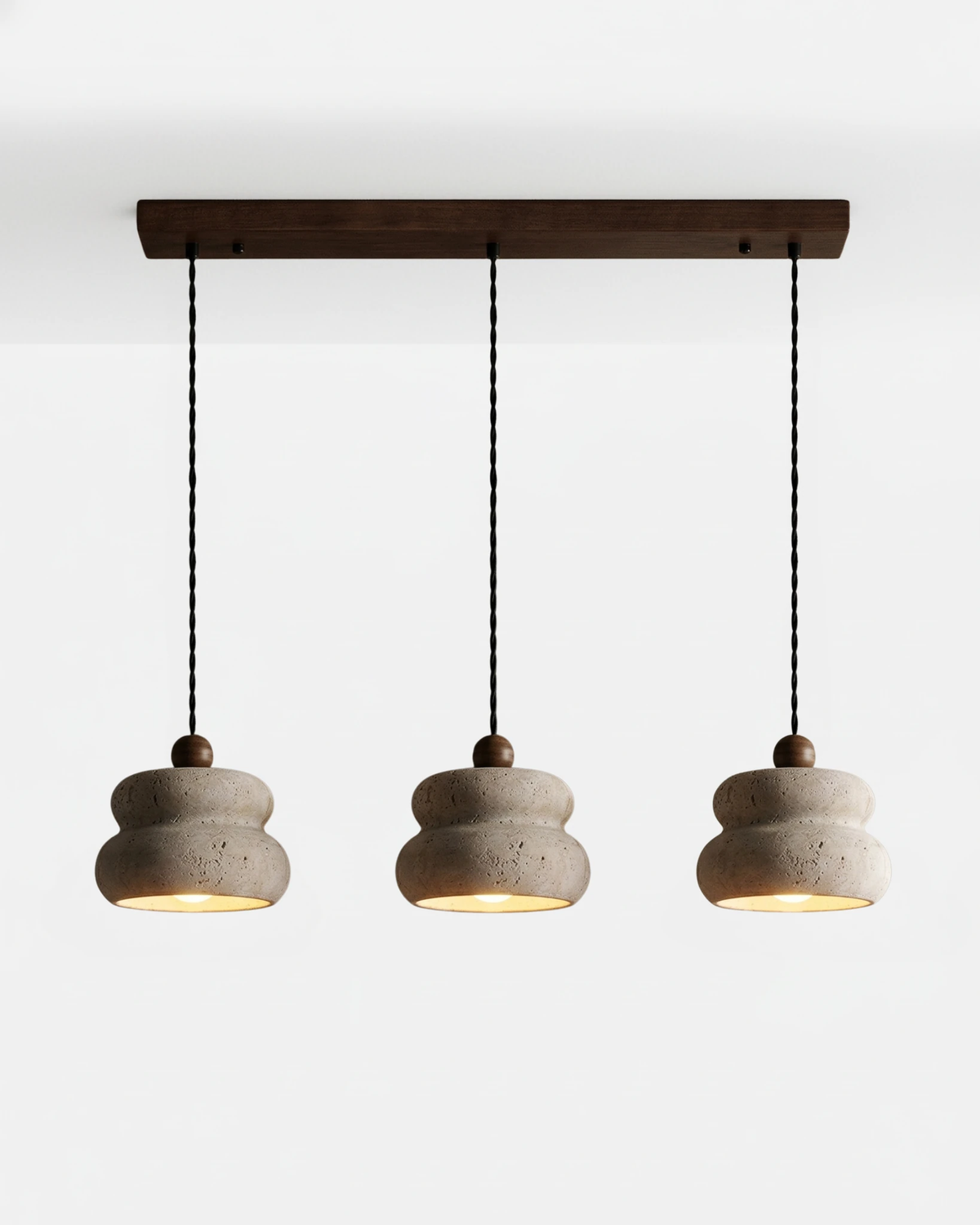 Travertine pendant light SOVA No.05 Triple Cluster, three cream pebble pendants hung from a walnut bar, switched on