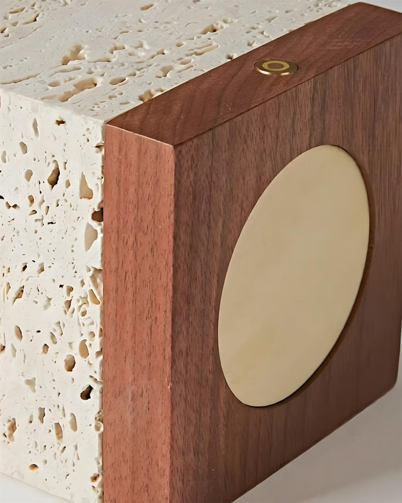 Close-up of the walnut base corner with a round brass disc on the MORA No.05 travertine table lamp