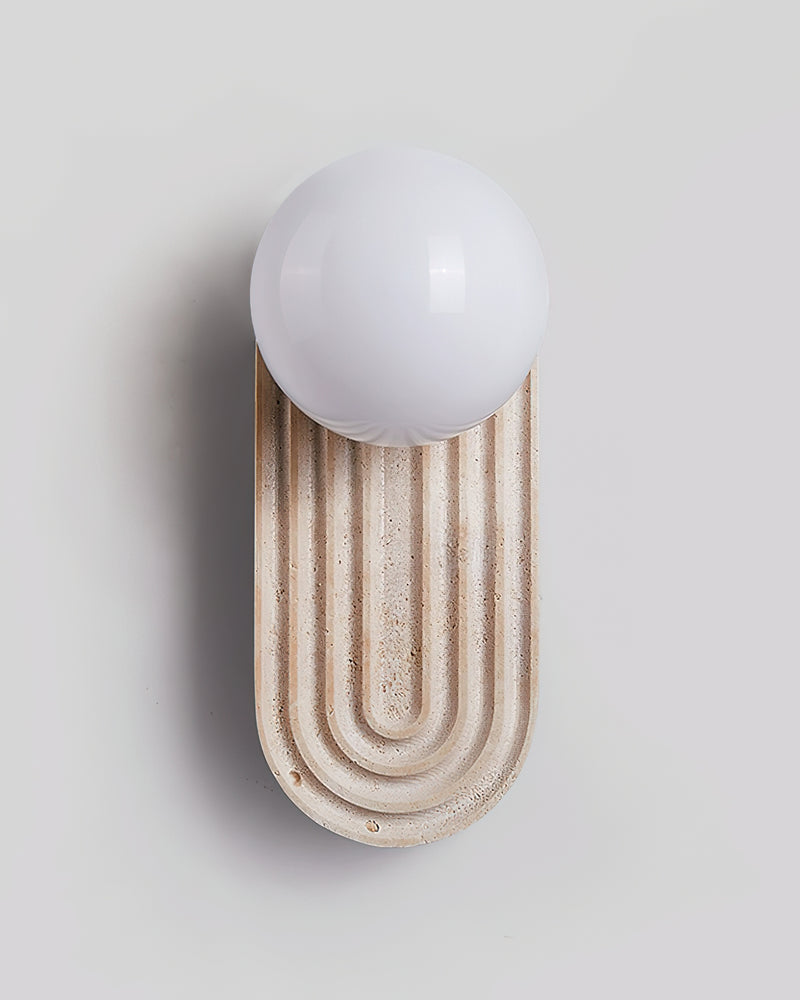 Travertine wall sconce ARCA No.01, unlit white globe on a fluted travertine arch, angled view on white