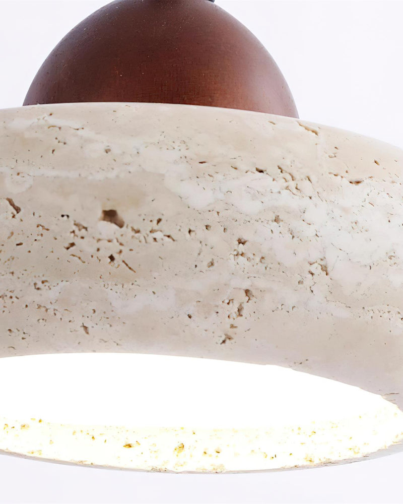 Close-up from below of the BASSO No.01 travertine wall sconce showing the lit diffuser inside the stone ring