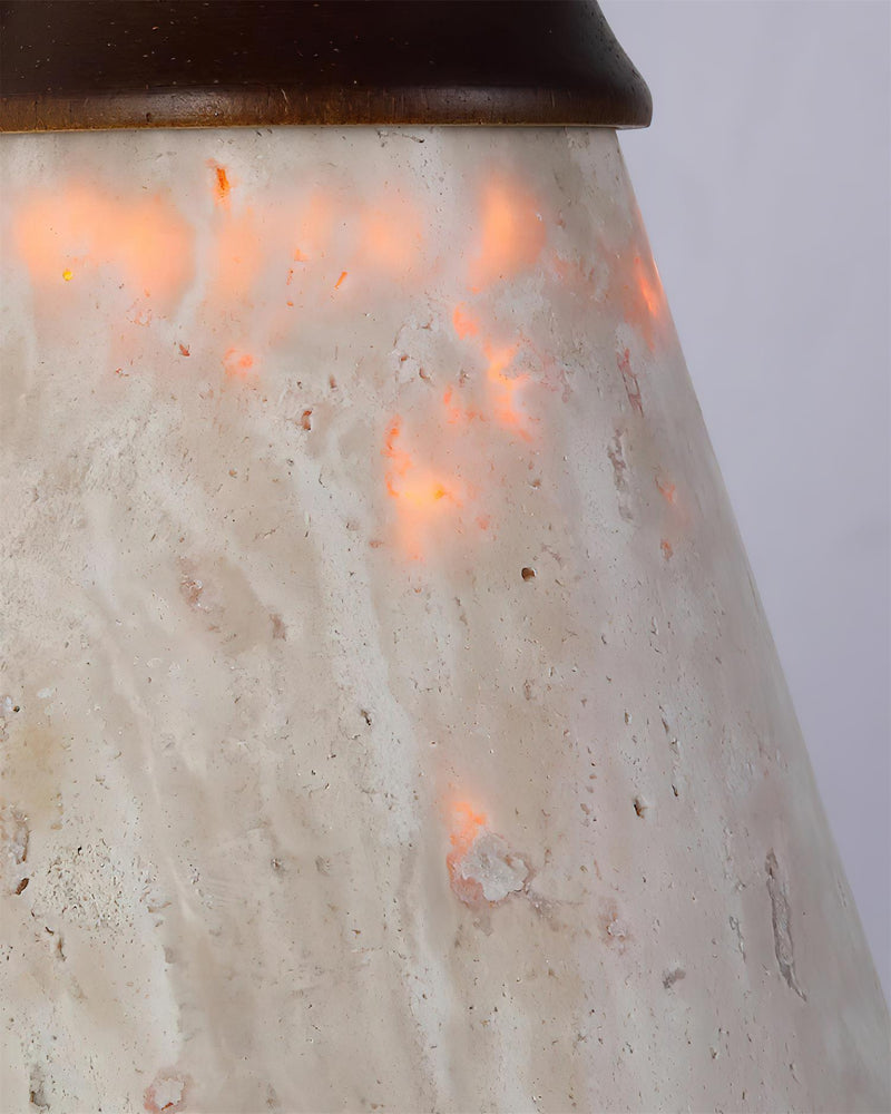 Close-up of the pitted yellow travertine cone shade of the CONA No.03 travertine wall sconce, lit from within