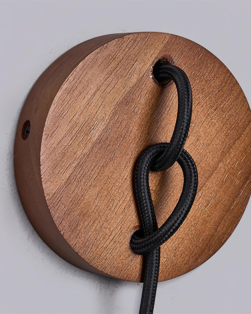 Close-up of the knotted black cord on the round walnut canopy of the travertine wall sconce CORTO No.02