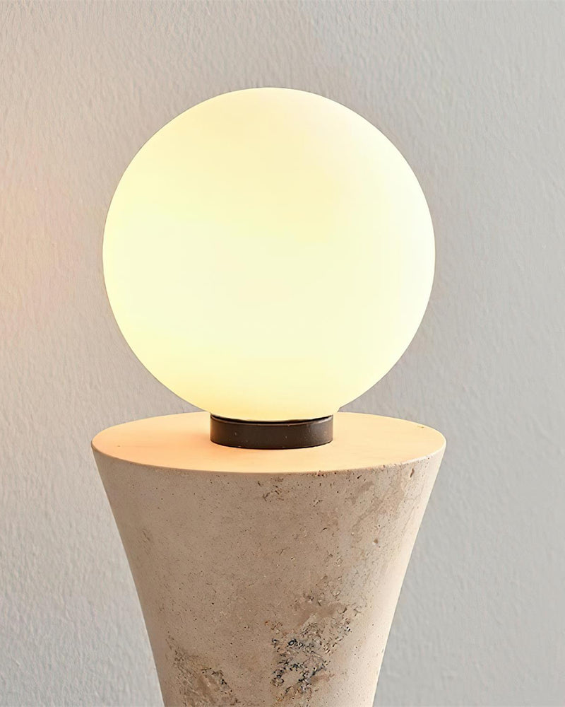 Close-up of the glowing opal globe sitting on the travertine cone of the travertine wall sconce VETTA No.01