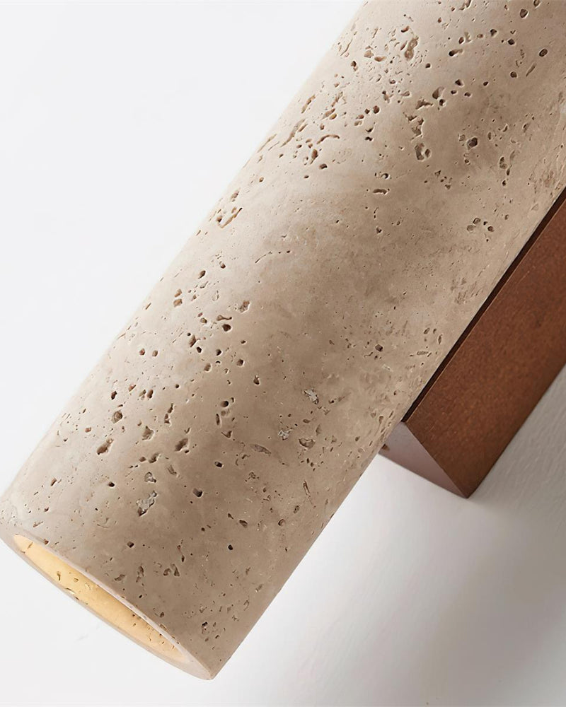 Angled close-up of the travertine wall sconce STELO No.02 column and walnut back with the lens visible