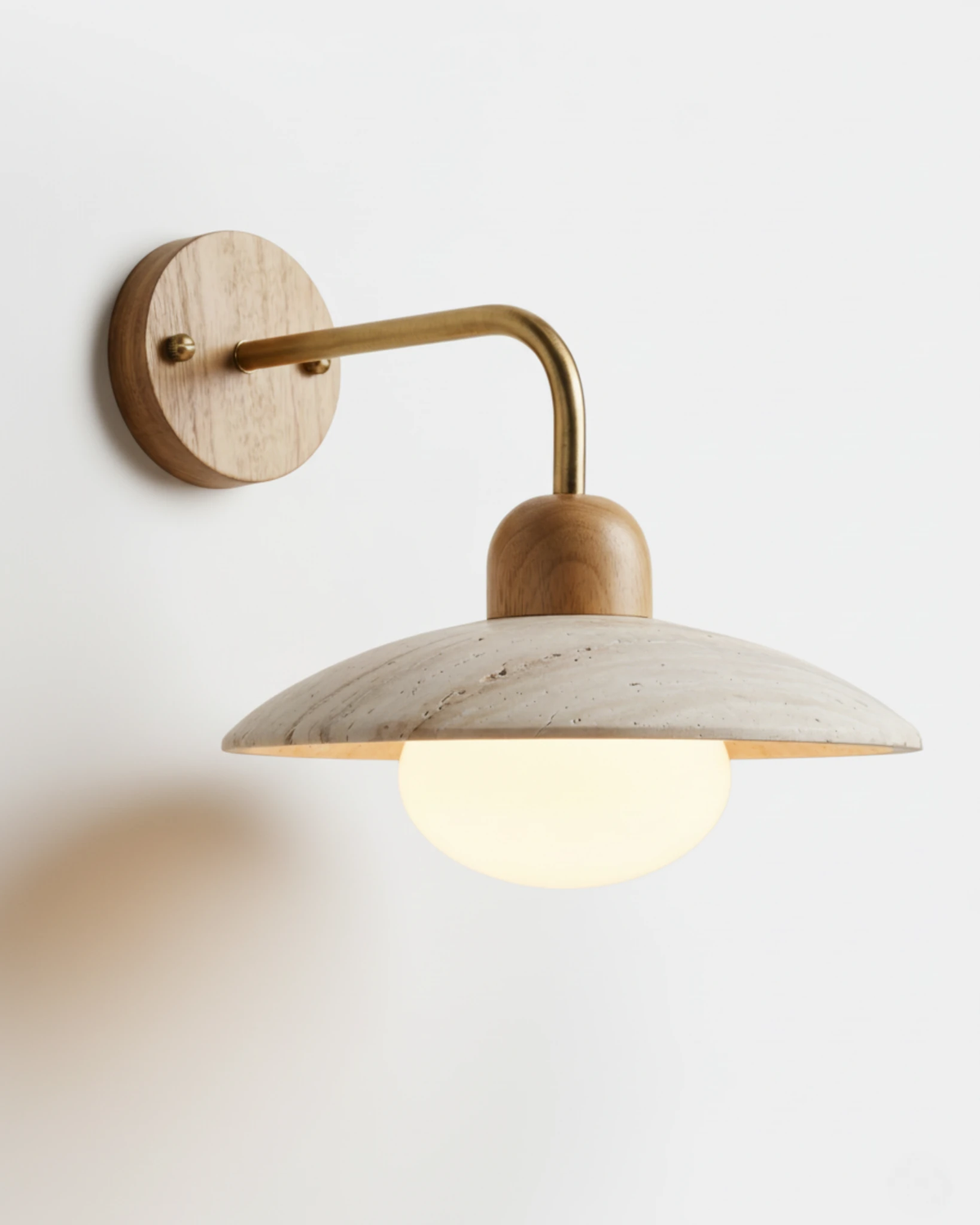 Travertine wall sconce IVERA No.01 with natural wood cap and brass arm, opal globe under a travertine disc, lit