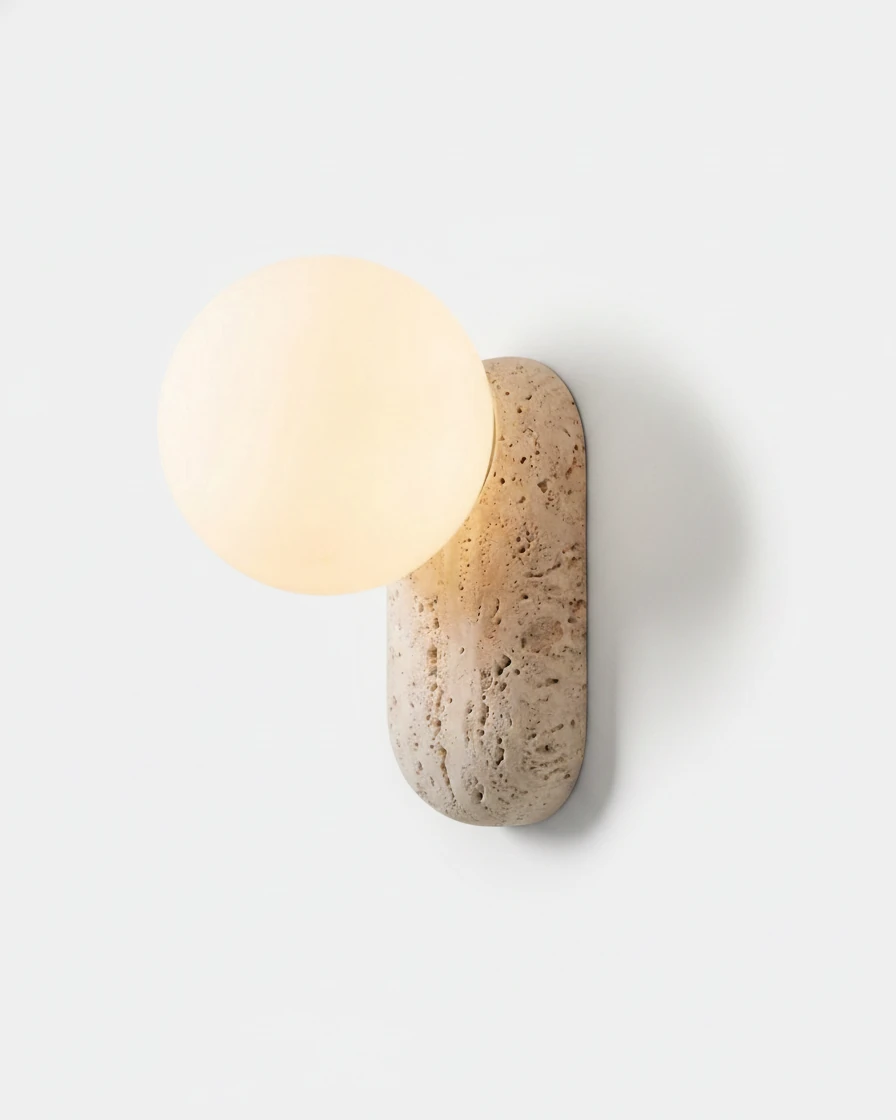Travertine wall sconce PERLA No.01, oblong cream travertine block holding a glowing opal glass globe
