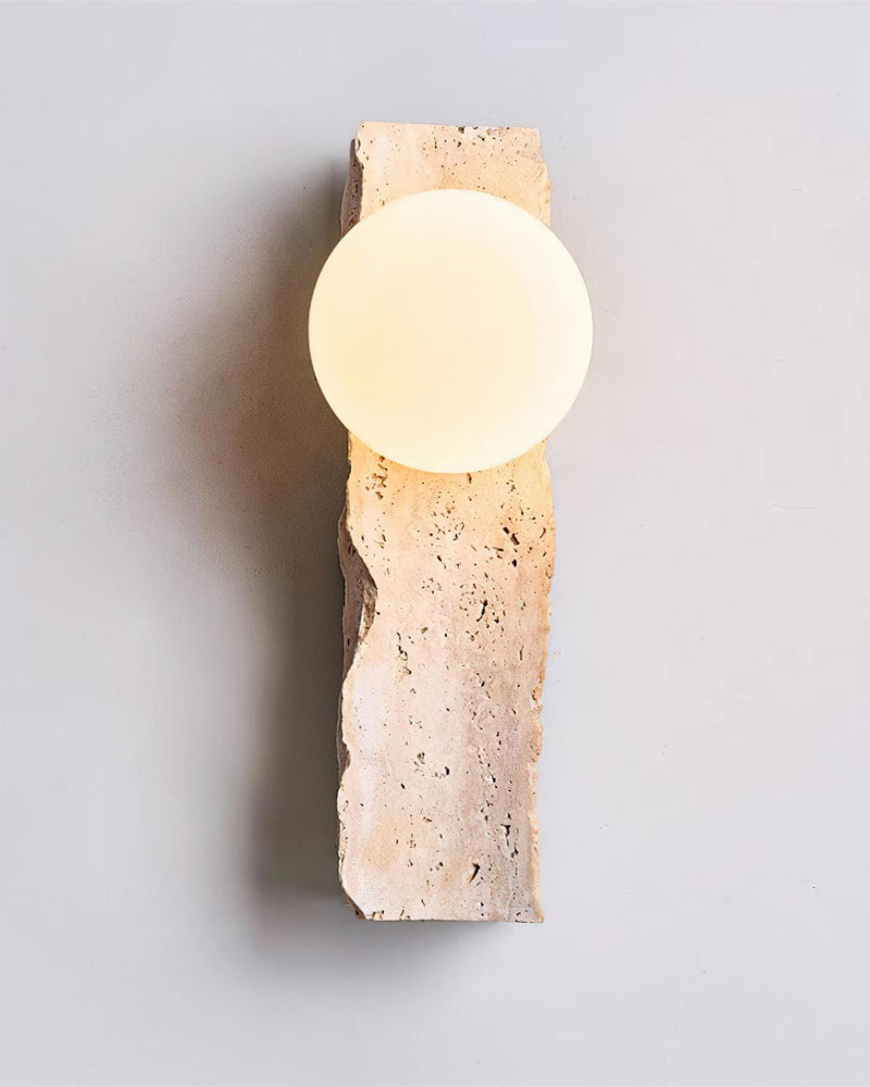 Travertine wall sconce KANSO No.03 seen head-on, lit opal globe mounted on a rough vertical stone slab
